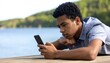 © Bagas - Young person engrossed in mobile phone near water