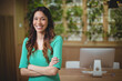 © WavebreakMediaMicro - Female office professional smiling while crossing arms at desk with plant wall, copy space