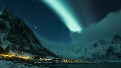 Wall Mural - Colorful aurora borealis lights in a snowy landscape with mountains and houses, under the starry sky.