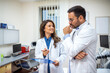 © Graphicroyalty - Two doctors in white coats have a thoughtful discussion in a bright medical office. The female doctor is holding a clipboard while the male doctor listens attentively.