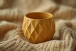 © AlparadiseDesign - Mustard yellow decorative pot on a knitted fabric.