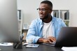 © Focus Prime - Handsome african american man working on laptop computer in home office setting desk