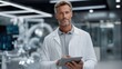 © pixs4u - A confident scientist in a lab coat holding a tablet, ready to discuss innovative research in a modern laboratory.