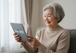 © md - An elderly asian woman enjoys using her tablet at home her face lit with a happy smile