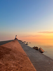 Wall Mural - the sun sets over lake michigan as the viewer takes a walk out to a light house in the distance.