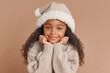 © Tabitha - cute happy little black girl with her chin in her hands wearing a beige santa hat and sweater