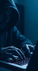 Wall Mural - close-up of hands typing on illuminated laptop keyboard, person wearing dark hoodie, low-light setti