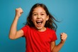 © Marica - Joyful young girl celebrating victory with enthusiastic fist pump gesture in vibrant studio setting with positive energy