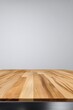 © Aira - A close-up view of a light brown wooden surface with a metallic edge against a muted gray backdrop. The wood grain is prominently displayed, showcasing a smooth, clean texture