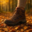 © Jeab - Close up of a brown hiking boot stepping on fallen autumn leaves in a forest setting