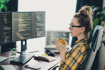 female programmer working on coding tasks at a modern workspace with multiple computer screens and h