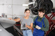 © JackF - Girl who owns car talks about problems to an auto mechanic at a car service center