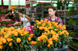 © JackF - Careful middle-aged saleswoman holding crossandra in flower-pots in plants market