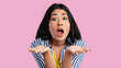 © Prostock-studio - Portrait of surprised expressive young asian lady gazing at camera in amazement with opened mouth, gesturing, spreading hands, astonished speechless woman impressed by offer, pink studio background