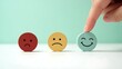 © Niloy - Finger pointing to a happy face emoji egg among sad and neutral faces representing customer feedback