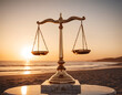 © Hasnain Raza - A golden scale on marble with ocean and sunset symbolizing justice