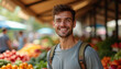 © Olga - Young smiling man enjoying fresh produce at an outdoor local farmer's market, celebrating healthy living.