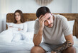 © Prostock-studio - Sexual dysfunction. Sad husband holds his head, upset wife lying on bed in bedroom