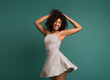 © Prostock-studio - Happy african-american woman in dress dancing on turquoise background