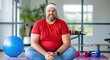 © Ganesha88 - Overweight man in red shirt sitting cross legged on yoga mat smiling happily in gym