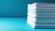 © Tina - A stack of white paper sheets on a blue background. The papers are neatly arranged and appear clean and crisp.