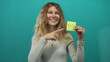 © Krakenimages.com - Woman uses her hand for pointing in a studio space, presenting blonde young pose with note showing yellow tax reminder against a teal backdrop.