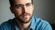 © Arif - Close Up Portrait of a Young Man with Beard Wearing Glasses and a Blue Denim Shirt Looking Off Into the Distance with a Thoughtful Expression