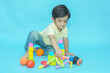 © GAJENDRRA BHATI  - Indian child boy playing with colorful toys for mental growth isolated against blue background. 2-3 year playful kid having fun while sitting on the floor, Childhood. Copy space