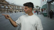 © Krakenimages.com - Young man gestures on a bustling city street wearing a white shirt with people and architecture blurred in the background