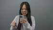 © Krakenimages.com - Chinese woman frustrated with phone isolated against grey background expressing anger and disappointment.