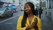 © Krakenimages.com - Woman standing at a bustling bus stop in an urban setting wearing a yellow shirt with a red double-decker bus in the background