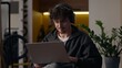 © Yuliia - Concentrated Caucasian guy working laptop at home man freelancer programmer chatting website designer in headphones typing online application hipster developer using computer male playing virtual game