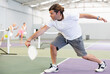 © JackF - Sporty man pickleball tennis player trains on the indoor court using a racket to hit the ball