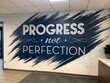 © Mizanur - Inspiring motivational wall art with the quote progress not perfection in a modern office setting