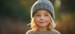 © Kazakov - The charming child in a cozy sweater and warm hat outdoors.