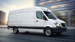 © MK studio - A white delivery van moves swiftly through a city street, passing by contemporary buildings. The scene captures the hustle of urban transportation during daylight
