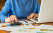 © Nanci - Businesswoman is working with financial data, using calculator and laptop, making calculations and analyzing graphs and charts, developing investment strategy