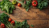 Top view of assorted fresh vegetables including greens, tomatoes, and herbs arranged on a rustic wooden table surface
