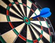 © Insyaallah - Close-up of a dartboard with a blue dart in the bullseye
