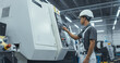 © Gorodenkoff - Asian Male Engineer in a White Hard Hat Operating a CNC Milling Machine in a Modern Factory. Young Technician Inserting Parameters into the Computer, Automating Production Line