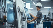 © Gorodenkoff - Asian Male Engineer in a White Hard Hat Operating a CNC Milling Machine in a Modern Factory. Young Technician Inserting Parameters on a Touch Screen Display, Automating Production Line