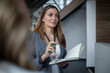© Migma_Agency - Businesswoman leading a meeting, holding notebook and pen