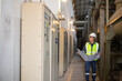 © JD Studio - Engineer inspects gas insulated switchgear panel inside power station with focused attention and safety gear on bright industrial corridor