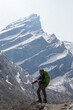 © Rizky - Young asian female hiker carrying mountain backpack and using trekking pole took photos after successfully hiking to Annapurna Base Camp, with the snow-capped Himalayan peaks visible in the morning