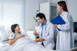 © Wasana - A woman is laying in a hospital bed with a doctor