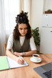 © LIGHTFIELD STUDIOS - Curly-haired young woman immersed in study at her stylish apartment in the afternoon