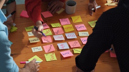 Wall Mural - top down aerial view of creative people hands writing idea on sticky notes at meeting table. close u