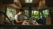 © Taniana Fomina - Young man working on laptop in cozy camper van surrounded by nature