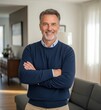 © picturehome - Happy confident middle aged senior man standing with arms crossed at home. Smiling older mature 50 years old handsome man looking at camera posing in modern house living room. Portrait.