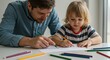 © Image - A father and his child are drawing on a white table with coloring pencils in a bright, naturally lit room.